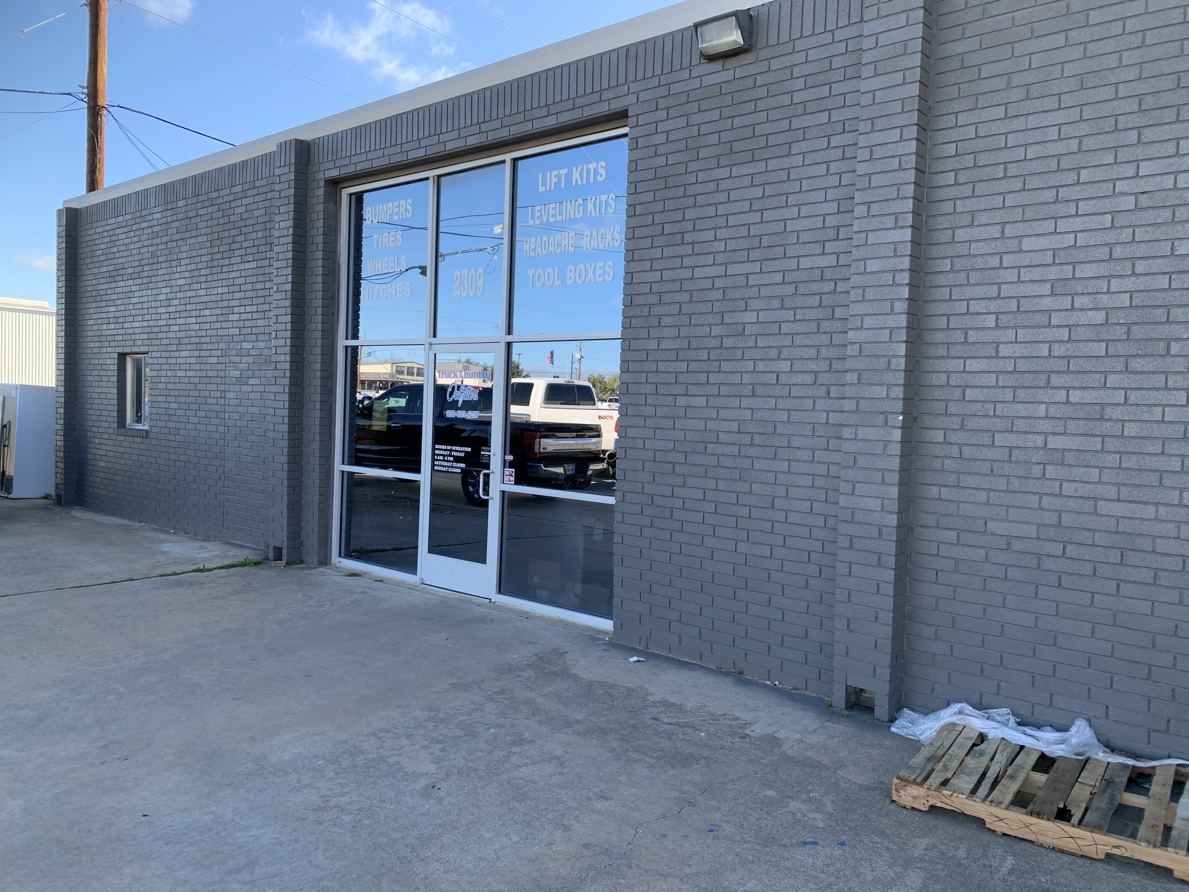 Truck Country Outfitters store exterior — gray brick building at 2309 Commerce St, Marble Falls TX with services listed on glass